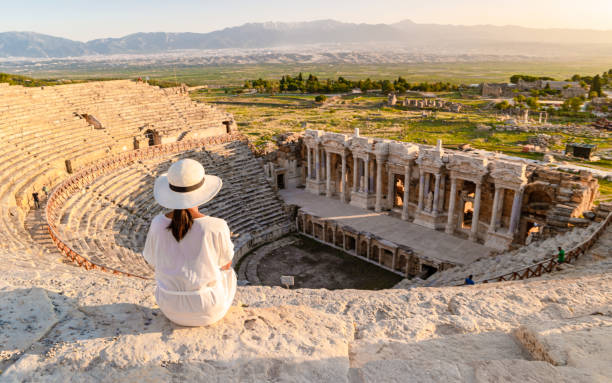 Hierapolis ancient city Pamukkale Turkey, young woman with hat watching sunset by the ruins Unesco stock photo
