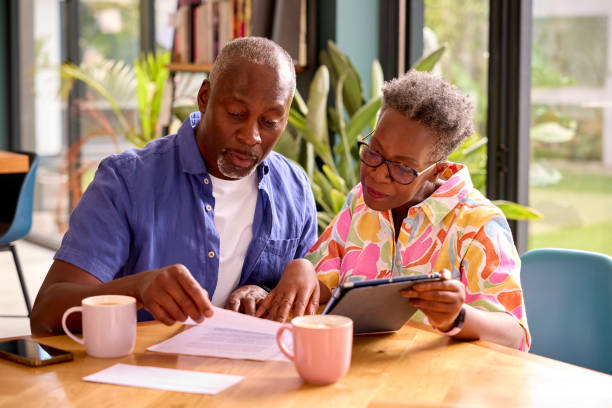 istock Senior Couple Sitting Around Table At Home Reviewing Finances Using Digital Tablet 1421263070