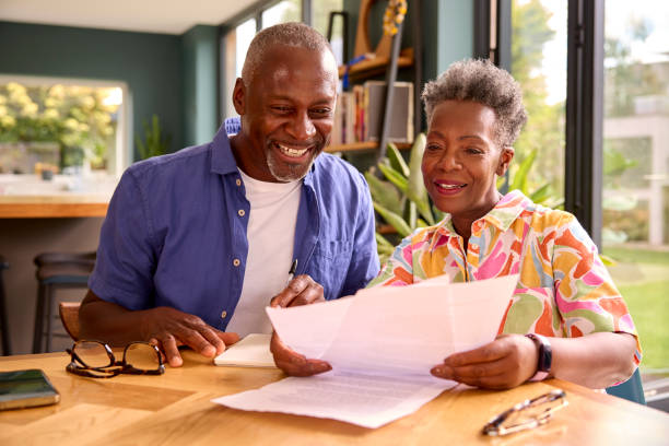 Smiling Senior Couple Sitting Around Table At Home Reviewing Finances stock photo