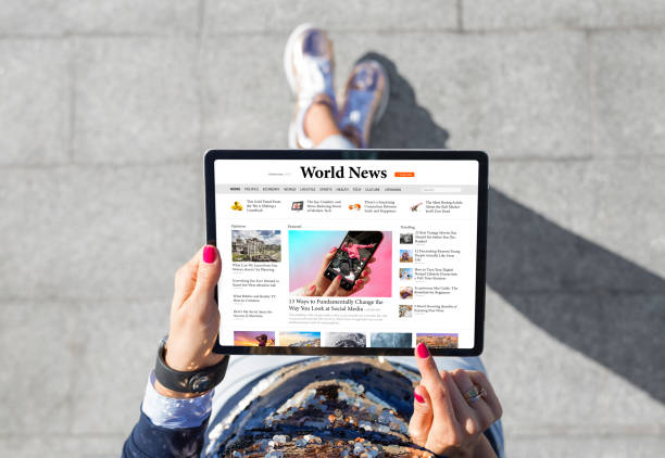 mujer de pie al aire libre y leyendo noticias en una tableta - mujer leyendo periodico fotografías e imágenes de stock