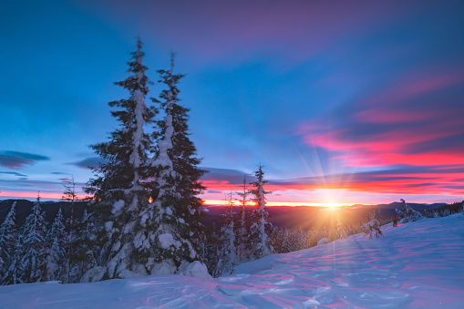 Frozen winter sunrise in a high mountains with enchanted red clouds in a sky.