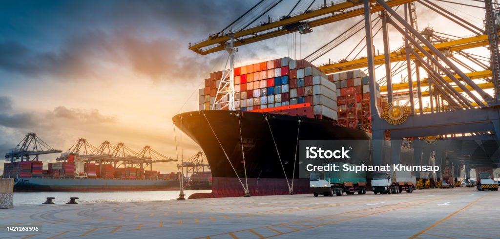 crane loading cargo container from truck to container ship in the international terminal logistic sea port concept freight shipping by ship Cargo Container Stock Photo