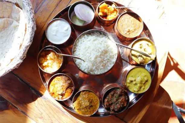 Dham - Traditional food of Himachal Pradesh. Himachali kangri dham thali includes Kaddu ka khatta, Chane ka Madra, sepu vadi, maash dal, Rajma, salad, rice, or Mitha Bhaat. served with Roti and pickle