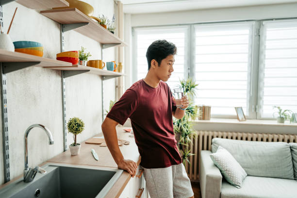 istock Young Man Drinking Water After Exercising At Home 1421271271