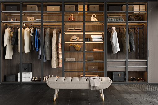 Close-up View Of Walk-in Closet Bench And Wardrobe With Clothes, Boxes, Bags And Shoes