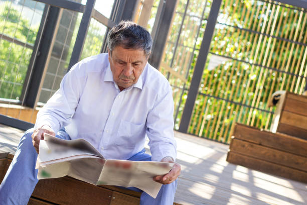 istock Elderly man reading a newspaper outdoors 1421272877