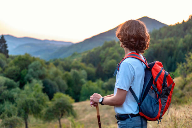 istock Young adult man hiking at mountain range during sunset with backpack 1421273727