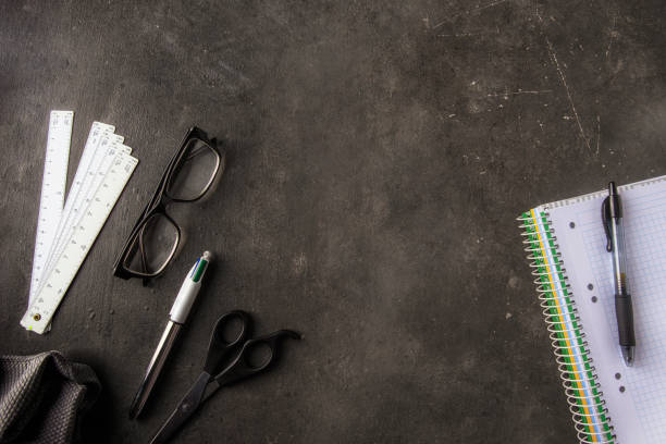 istock Back to school and studying concept. Different school and university accessories pen, glasses, notebook, rules and board cleaning cloth  on dark blackboard 1421273772