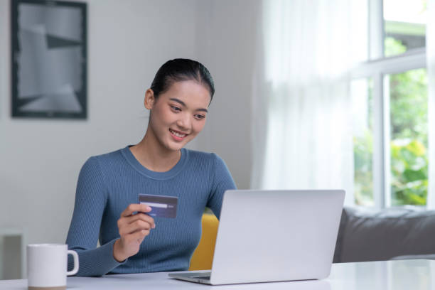 istock Young Asian woman holding credit card and using laptop computer. 1421274550