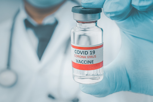 Male Doctor wearing PPE with a stethoscope on shoulder and holding  COVID-19 vaccine CORONA vaccine concept Healthcare and Medical