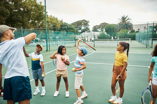 istock Tennis, education and learning students or kids training, exercise or workout with coach in tennis court. Fitness, wellness and health sport instructor teaching team sports game. 1421280565