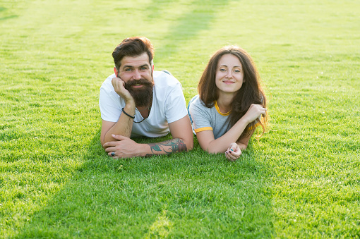Carefree couple enjoying sunny day relaxing on green meadow, summer vacation concept.