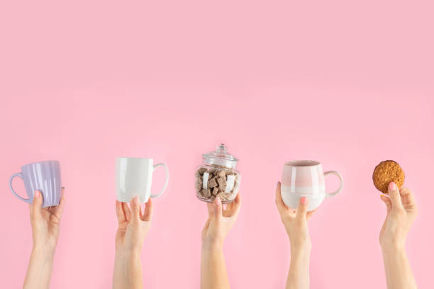 istock Arms raised up holding coffee cup on pink background. 1421282930
