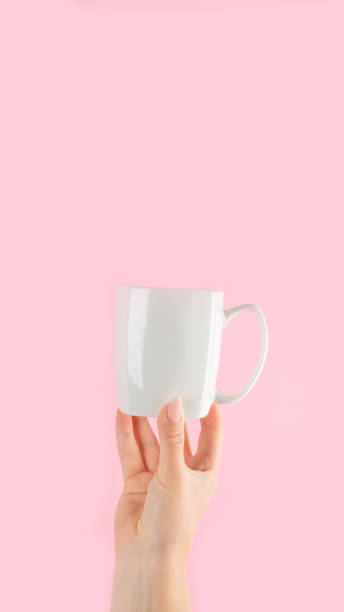 istock Arms raised up holding coffee cup on pink background. 1421282986