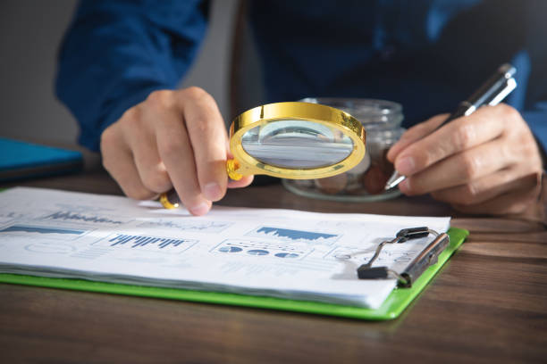 istock Man holding magnifying glass with a graphs and charts. Business. Analysis 1421283601