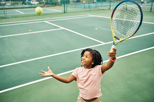 African girl learning tennis on court at school, training for sports game and excited for sport competition. Student, athlete and kid happy about fitness education and cardio exercise for match