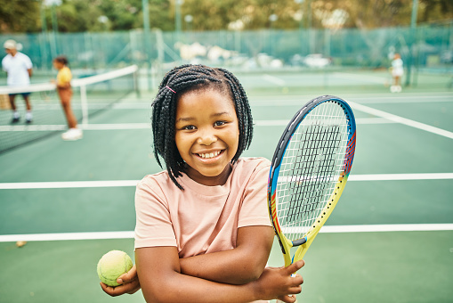 Portrait of a happy youth tennis girl with sports equipment for sport growth, development and progress on a tennis court. Child with tennis racket and ball at training camp or club for skill practice