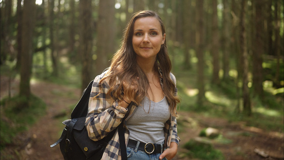 Woman hiking in a nordic forest. She is walking in the forest with a backpack.