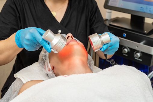 Beautician doing skin care with red light therapy