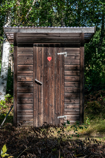 Skelleftea, Sweden, Aug 22, 2022 A wooden outhouse next to a beach.