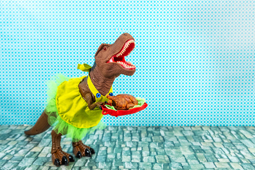 Toy dinosaur in a dress having a thanksgiving meal.