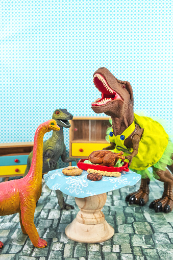 Toy dinosaurs in a dress having a thanksgiving meal.