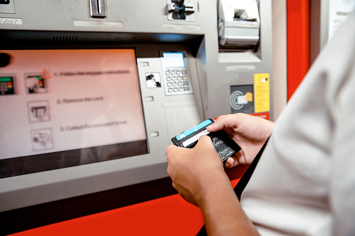 Male hands with open wallet using ATM Machine paying with credit card