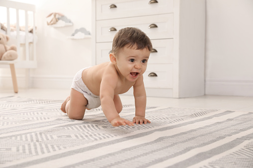 Cute baby crawling on floor at home