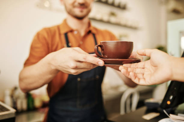 Hands of cafe basita giving cup of cappuccino to customer