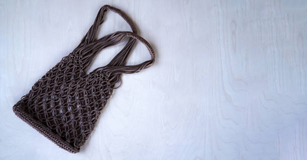 istock Brown string bag knitted in macrame technique from a knitted cord on a wooden background. Flat lay, top view. Zero waste and plastic free concept. A place for your text, advertising. 1421308755