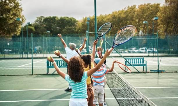 Children learning tennis in fitness class at school, training for sports game on court and kids in line for sport education. Students, friends and athlete playing on playground for competition stock photo