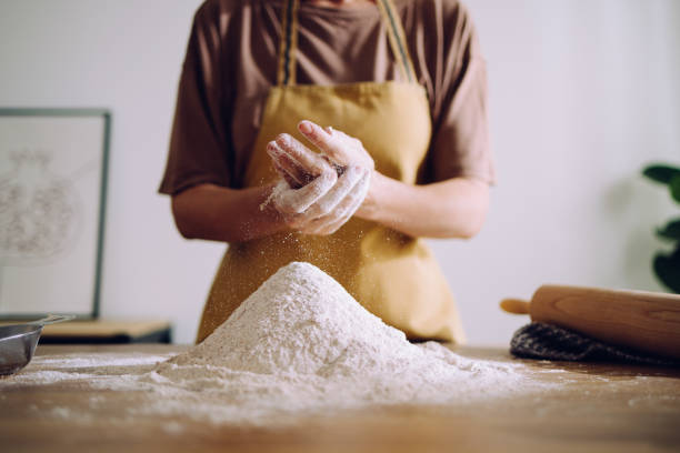 istock Anonymous Woman Adding and Preparing Flour for Kneading 1421310446