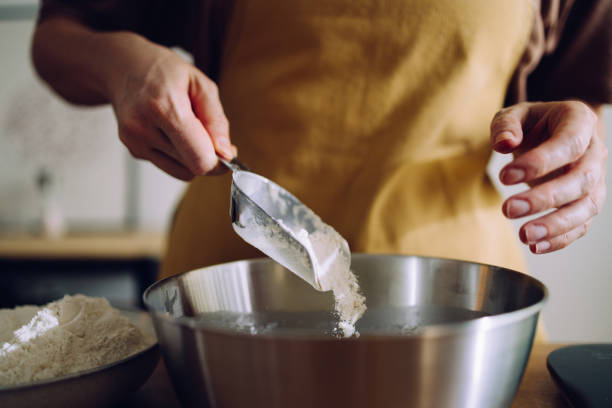 istock Anonymous Woman Baking at Home and Adding Flour to the Mix 1421310530
