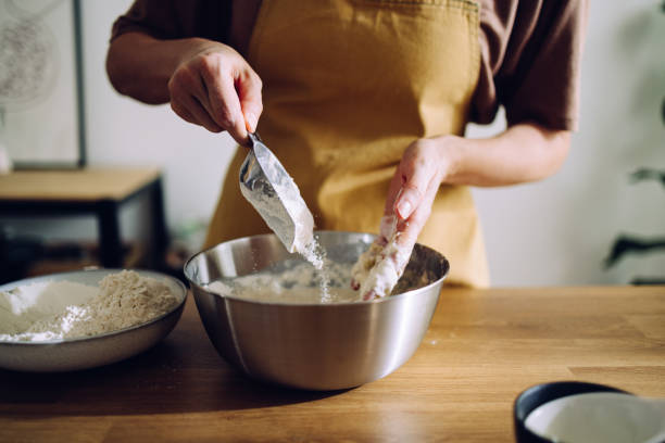 istock Anonymous Woman Baking at Home and Adding Flour to the Mix 1421310533