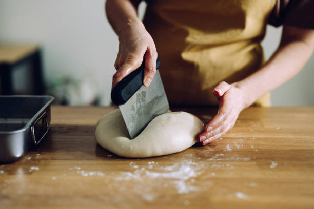 istock Female Baker Cutting Dough With a Dough Scrapper 1421310820