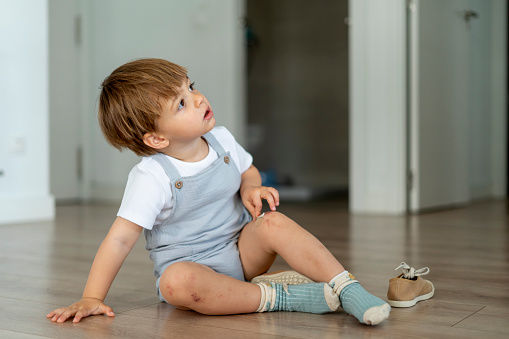 Adorable little boy sitting on the floor of his home