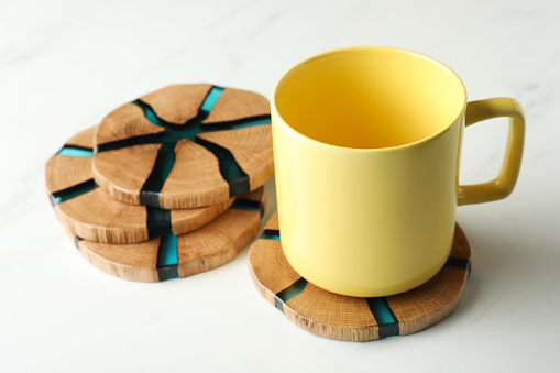 Mug and stylish wooden coasters on white marble table
