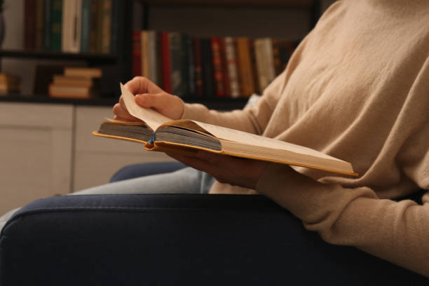 istock Young woman reading book in home library, closeup 1421312963