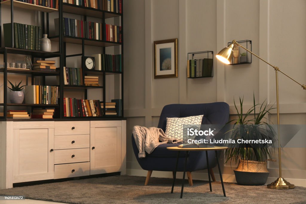 Cozy home library interior with collection of different books on shelves and comfortable place for reading Bookshelf Stock Photo