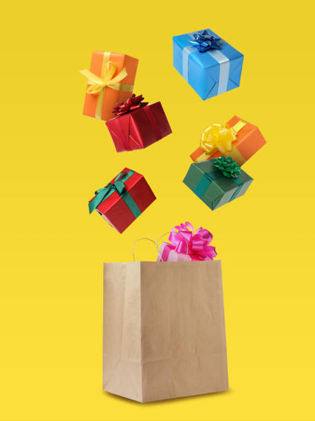 istock Many different gift boxes falling into paper shopping bag on yellow background 1421313656