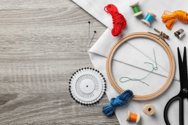 istock Embroidery hoop, fabric and other accessories on wooden table, flat lay. Space for text 1421314312