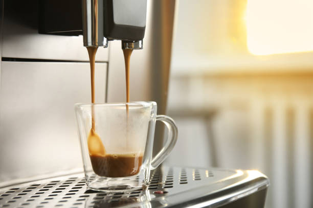 istock Espresso machine pouring coffee into glass cup against blurred background, closeup. Space for text 1421319699