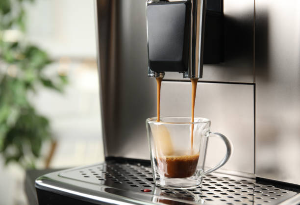 istock Espresso machine pouring coffee into glass cup against blurred background, closeup. Space for text 1421320031