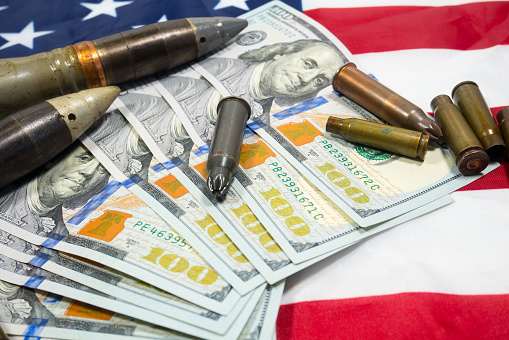 American flag with dollars money, bullets, shells, cartridges and projectiles on it. Lend-Lease concept.  Army concept. Sales of weapons and ammunition.\nMilitary industry, war, global arms trade.