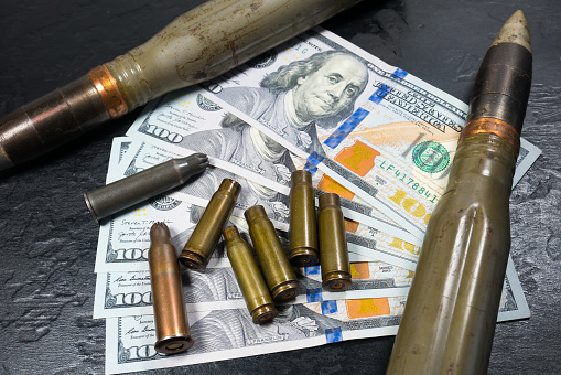 Dollars money, bullets, shells, cartridges and projectiles on black background. Lend-Lease concept.  Army concept. Sales of weapons and ammunition.\nMilitary industry, war, global arms trade.