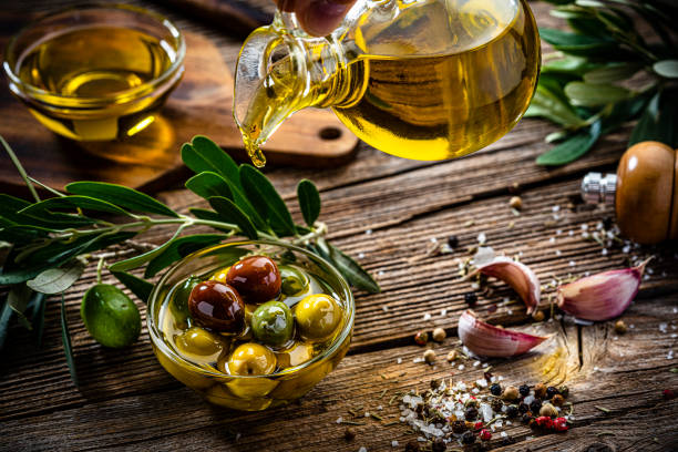 органическое оливковое масло первого отжима и оливки - cooking oil oil pouring olive oil стоковые фото и изображения