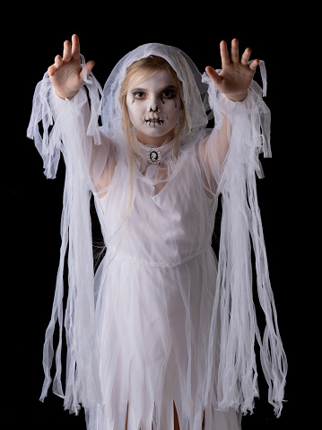 Little girl in Halloween ghost costume walking on you, studio isolated on black background