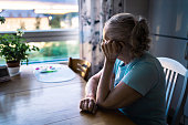 Sad old woman. Depressed lonely senior lady with alzheimer, dementia, memory loss or loneliness. Elder person looking out the home window. Sick patient with disorder. Pensive grandma.