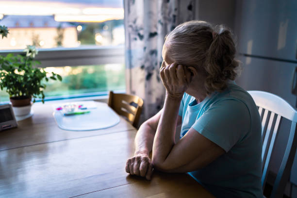 Sad old woman. Depressed lonely senior lady with alzheimer, dementia, memory loss or loneliness. Elder person looking out the home window. Sick patient with disorder. Pensive grandma. stock photo