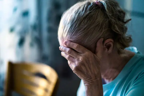 Photo of Sad senior old woman. Lonely from loss or sick with headache. Upset patient in retirement home with stress or pain. Alzheimer, depression, senility or dementia.